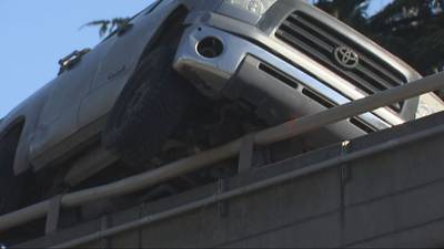 PHOTOS: Crash leaves truck precariously perched against guardrail