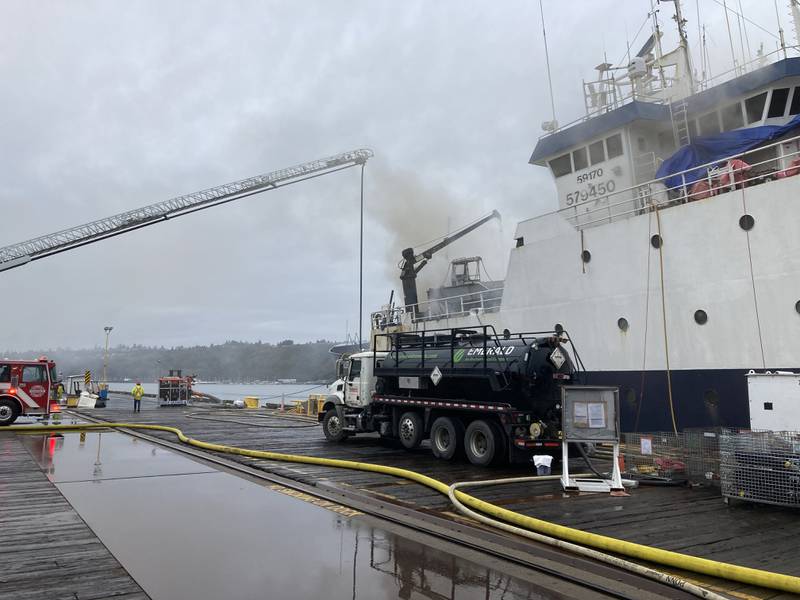 Smoke coming from a vessel with a firetruck and dock.