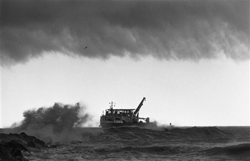 The giant salvage ship, the Stener Workhorse comes to port as storm clouds darken overhead and waves crash against the jetties at Port Canaveral, Florida on Friday, March 14, 1986. The Stener Workhorse was one of the largest ships being used for salvage work in an area where Space Shuttle Challenger crashed into the sea following the explosion that ripped it apart on January 28th. (AP Photo/Thom Baur)