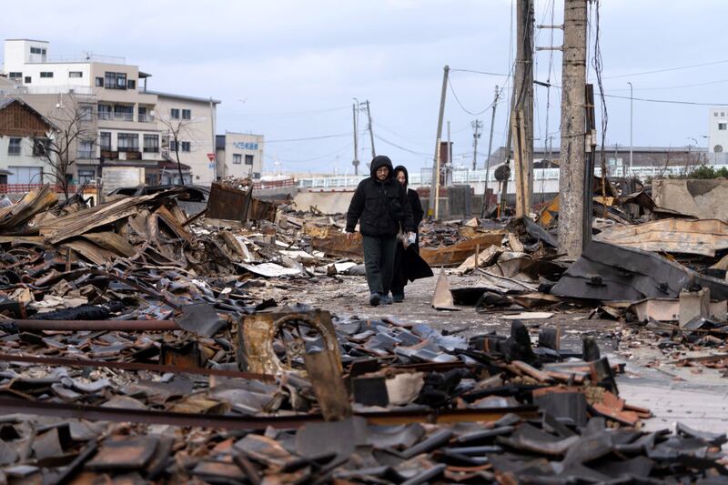 WAJIMA, JAPAN - JANUARY 05: A couple walks through the Asaichi Yokocho, or Wajima Morning Market, area after a fire incident following an earthquake on January 05, 2024 in Wajima, Japan. On New Year's Day, a series of major earthquakes reportedly killed at least 92 people, injured dozens more and destroyed a large amount of homes. The earthquakes, the biggest measuring 7.1 magnitude, hit the areas around Ishikawa, Toyama and Niigata in central Japan. (Photo by Tomohiro Ohsumi/Getty Images)