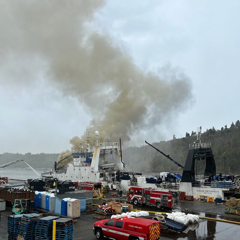 Smoke coming out of a boat next to a dock.