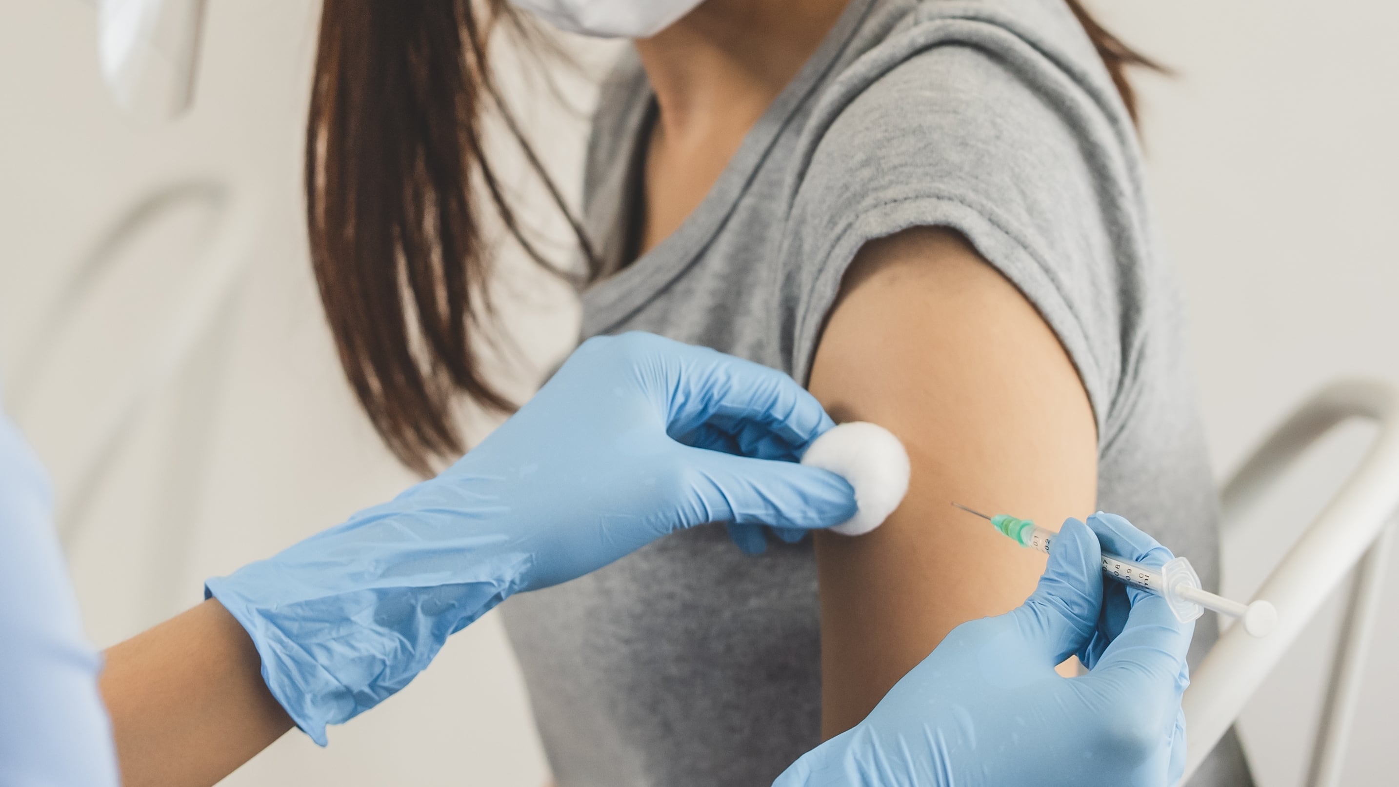 People getting a vaccination to prevent pandemic concept. Woman in medical face mask receiving a dose of immunization coronavirus vaccine from a nurse at the medical center hospital