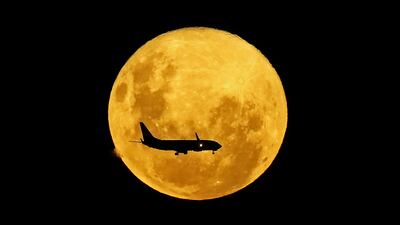 A plane passes in front of the full moon as seen from Curitiba, Brazil, on March 9, 2020.
