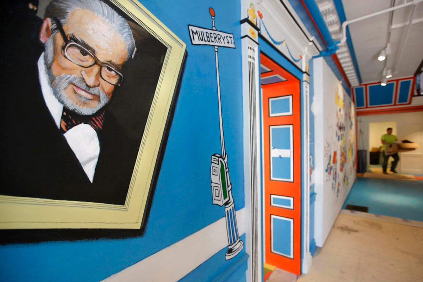 FILE - In this May 4, 2017, file photo, a mural that features Theodor Seuss Geisel, left, also known by his pen name Dr. Seuss, covers part of a wall near an entrance at The Amazing World of Dr. Seuss Museum, in Springfield, Mass. Dr. Seuss Enterprises, the business that preserves and protects the author and illustrator's legacy, announced on his birthday, Tuesday, March 2, 2021, that it would cease publication of several children's titles including "And to Think That I Saw It on Mulberry Street" and "If I Ran the Zoo," because of insensitive and racist imagery. (AP Photo/Steven Senne, File)