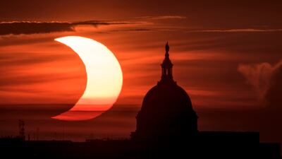 In this handout image provided by NASA, a partial solar eclipse is seen as the sun rises behind the Capitol Building on June 10, 2021, in Arlington, Virginia.