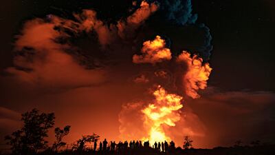 In this photo provided by the National Park Service, people watch an eruption from Hawaii's Kilauea volcano on the Big Island on Sunday, Dec. 20, 2020. The volcano shot steam and an ash cloud into the atmosphere which lasted about an hour, an official with the National Weather Service said early Monday, Dec. 21, 2020.