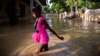 A girl wades towards her flooded home the day after the passing of Tropical Storm Laura in Port-au-Prince, Haiti, Monday, Aug. 24, 2020.