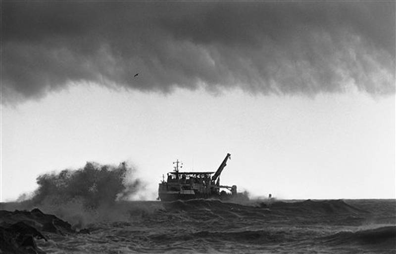 The giant salvage ship, the Stener Workhorse comes to port as storm clouds darken overhead and waves crash against the jetties at Port Canaveral, Florida on Friday, March 14, 1986. The Stener Workhorse was one of the largest ships being used for salvage work in an area where Space Shuttle Challenger crashed into the sea following the explosion that ripped it apart on January 28th. (AP Photo/Thom Baur)